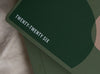 Close-up of the "From Little Things" variant of the 2026 MiGoals A5 Weekly Notes Diary. The dark green cover features bold white text reading "TWENTY-TWENTY SIX" with abstract geometric shapes in muted green and blush tones.