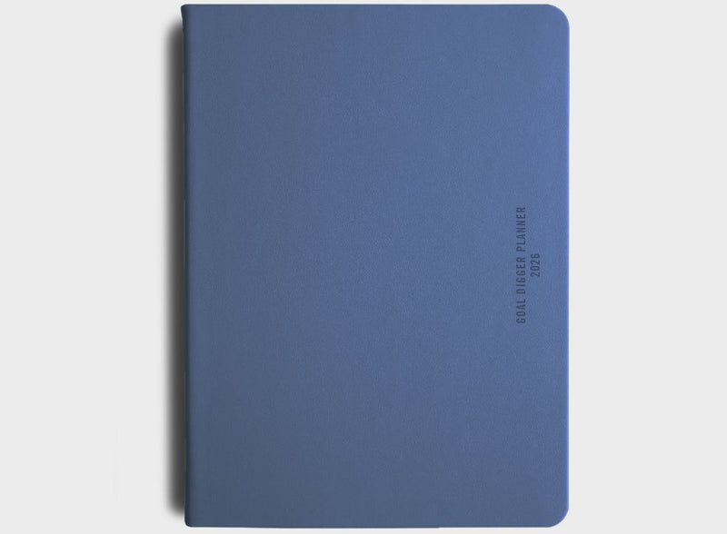 MiGoals 2026 Classic Diary in sea green with embossed “Goal Digger Planner 2026” on the cover, styled on a stone tray with a coffee cup and fabric backdrop.