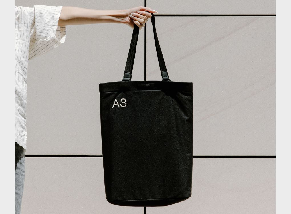 Woman holding an A3 Tote Bag in Black Ash to show its size for reference.