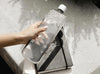 Original clear memobottle in Slim, full of water next to a notebook